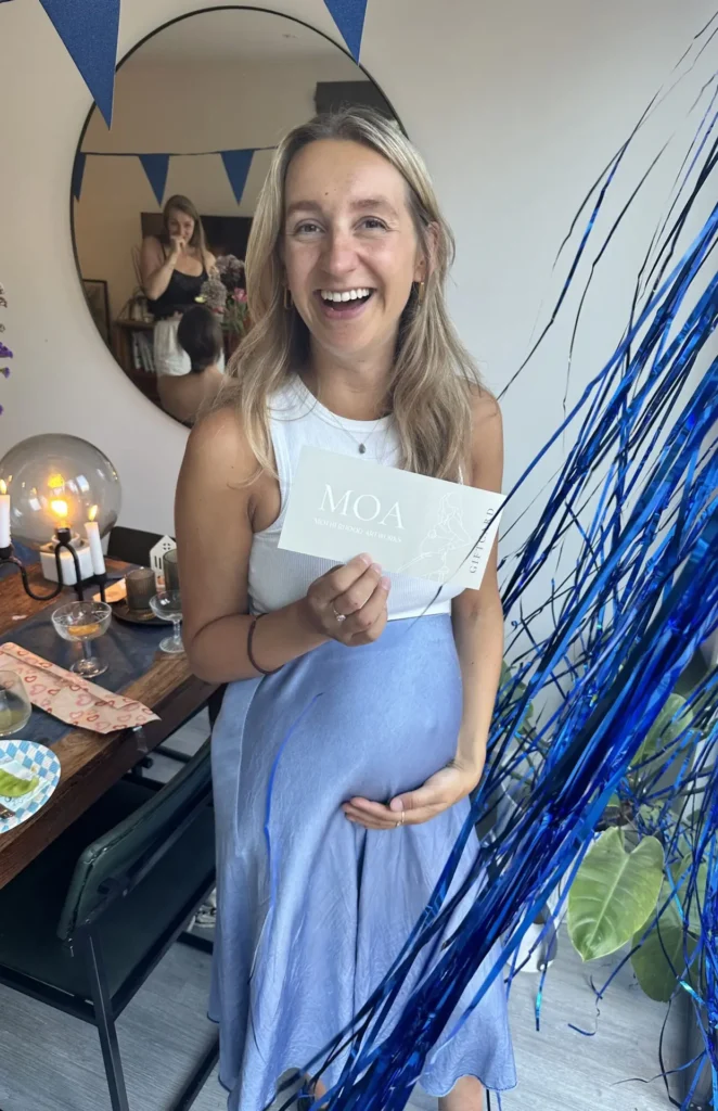 Zwangere vrouw met cadeaubon zwangerschapsbeeldje